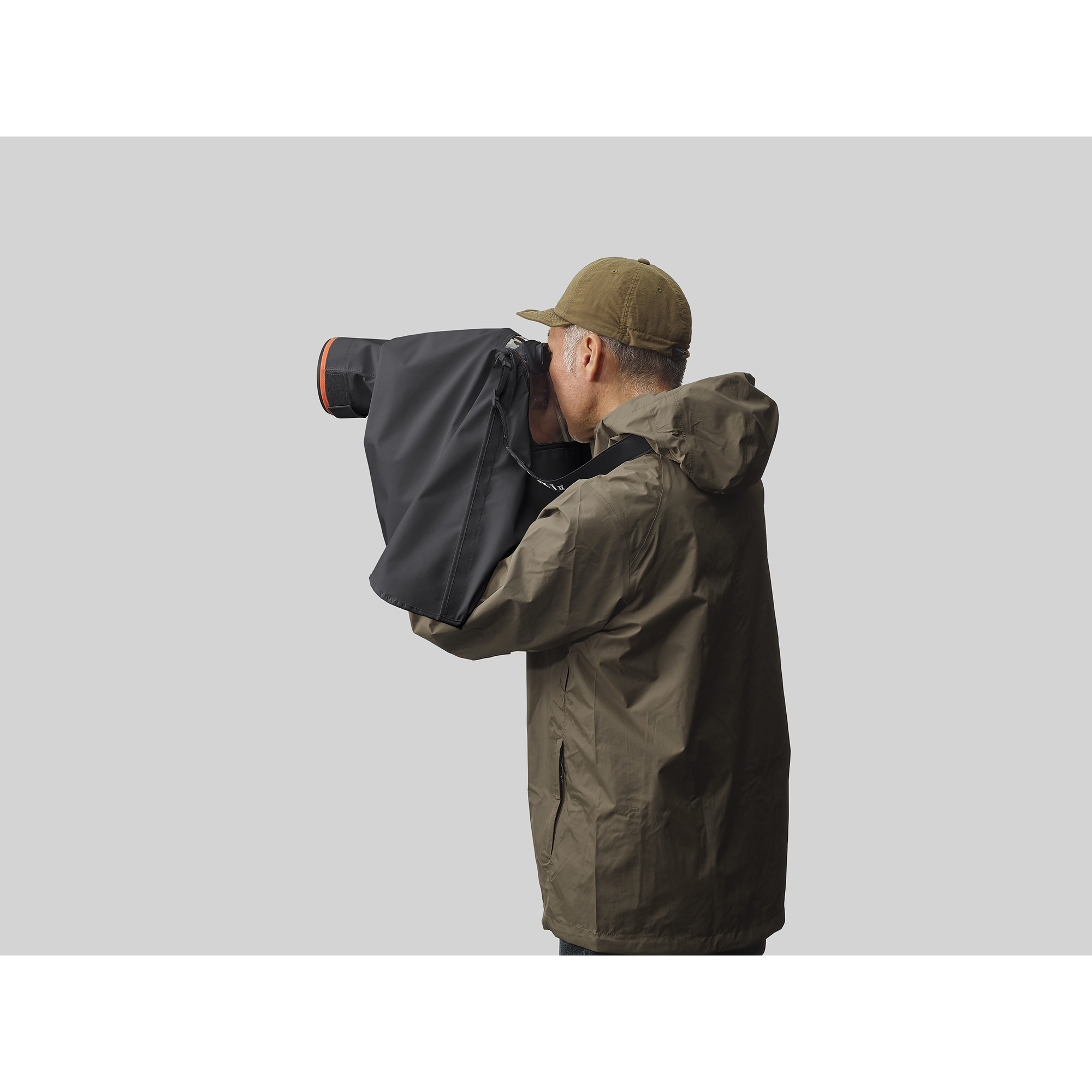 一位攝影師正在拍攝， Sony 相機套上黑色防雨罩，相機架在腳架上情境圖